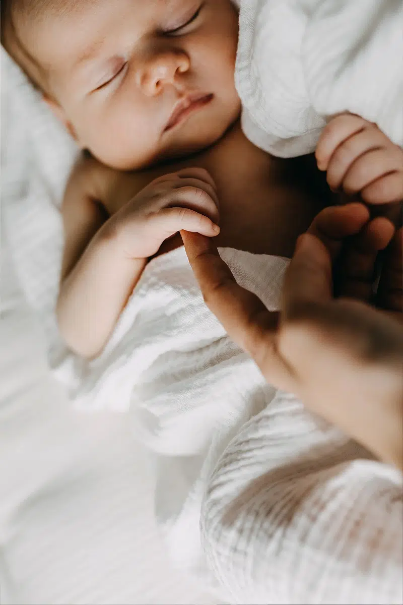 Bébé endormi tenant un doigt